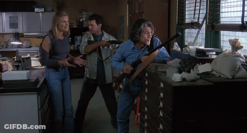 Man Holding Shotgun Next To Woman And Man In Messy Room GIF