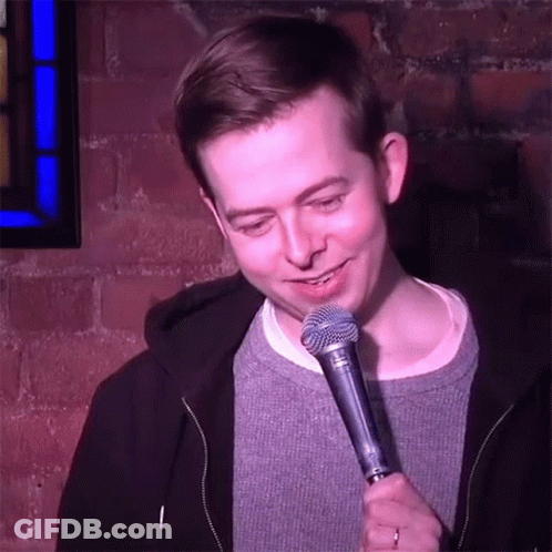 Man Holding Shure Microphone In Front Of Brick Wall GIF