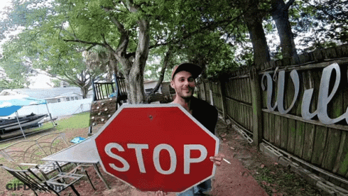 Man Holding Stop Sign In Front Of Fence GIF