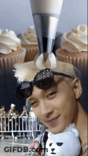 Man Holding Stuffed Animal Near Frosted Cupcakes GIF