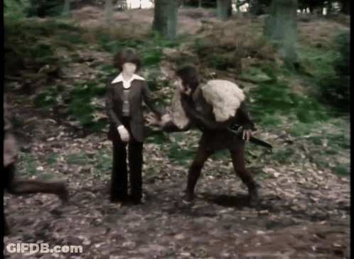 Man Holding Sword And Woman Holding Sheep In Woods GIF