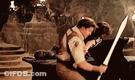 Man Holding Sword In Cave Woman On Table GIF