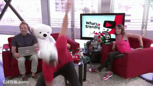 Man Holding Teddy Bear In Front Of TV Saying What's Trending GIF