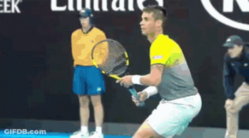 Man Holding Tennis Racquet In Front Of Emirates Sign GIF