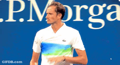 Man Holding Tennis Racquet In Front Of J.P. Org Sign GIF