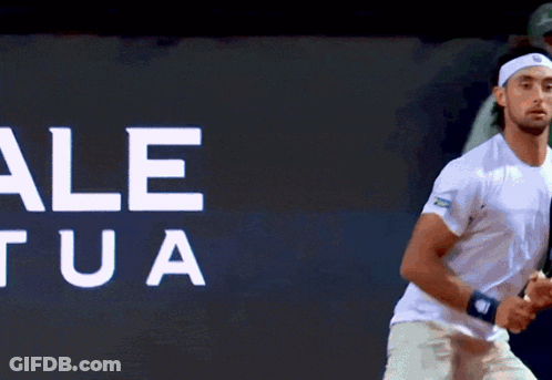 Man Holding Tennis Racquet In Front Of Wall Saying Le Ua GIF