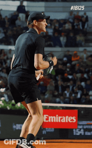 Man Holding Tennis Racquet On Court With Emirates Sign GIF
