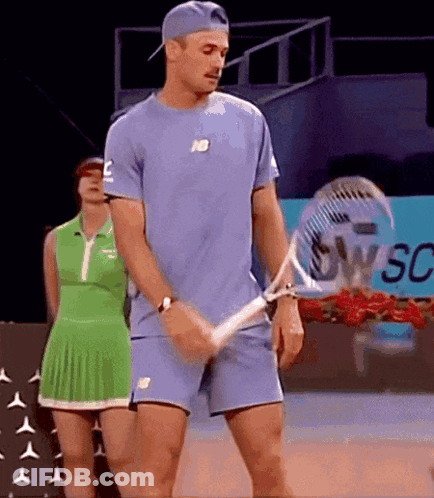 Man Holding Tennis Racquet Woman In Green Dress Behind GIF