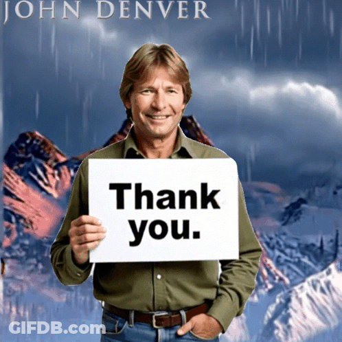 Man Holding Thank You Sign In Front Of John Denver Poster GIF