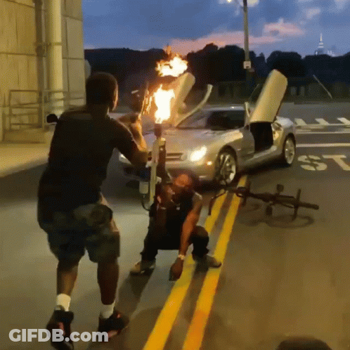 Man Holding Torch In Front Of Car With ST On Side GIF