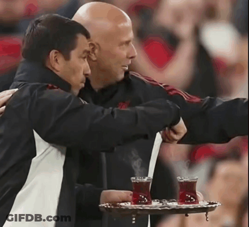 Man Holding Tray Of Tea Hugged By Another GIF