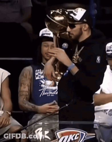 Man Holding Trophy In Front Of OKC Sign GIF