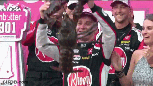 Man Holding Trophy In Front Of Rheen Sign GIF