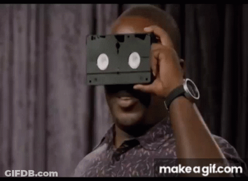 Man Holding VHS Tape Over Face GIF