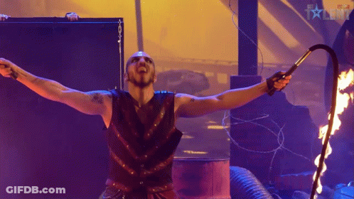 Man Holding Whip In Front Of Fire And BBC Talent Sign GIF