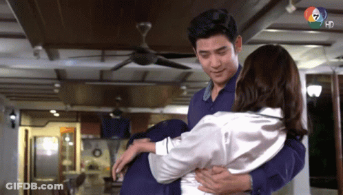 Man Holding Woman In Arms Under Ceiling Fan GIF