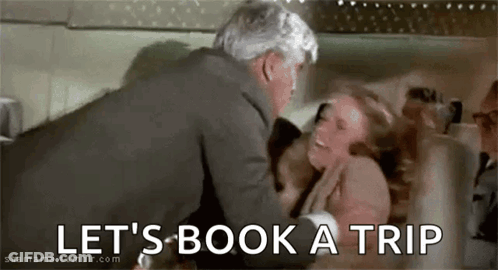 Man Holding Woman In Bed Saying Let's Book A Trip GIF