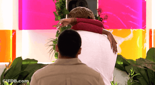 Man Holding Woman In Front Of Pink Wall GIF