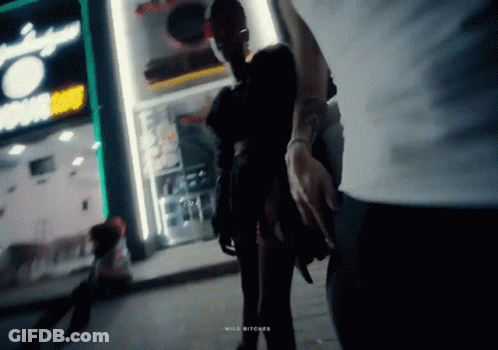 Man Holding Woman's Hand In Front Of Wild Bitches Store GIF