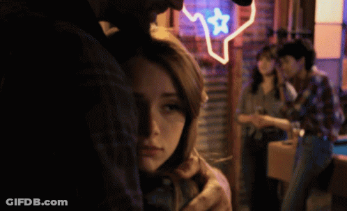 Man Hugging Woman In Front Of Texas Neon Sign GIF