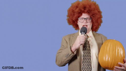 Man In Afro Wig Holding Pumpkin And Microphone Says Happy Halloween GIF