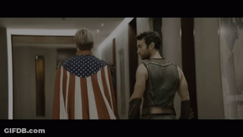Man In American Flag Cape Next To Superhero GIF