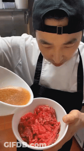 Man In Apron Holding Bowl Of Meat And Bowl Of Sauce GIF