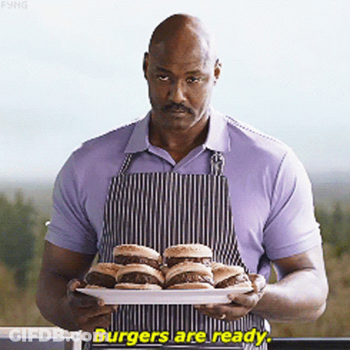 Man In Apron Holding Hamburgers Says Burgers Are Ready GIF