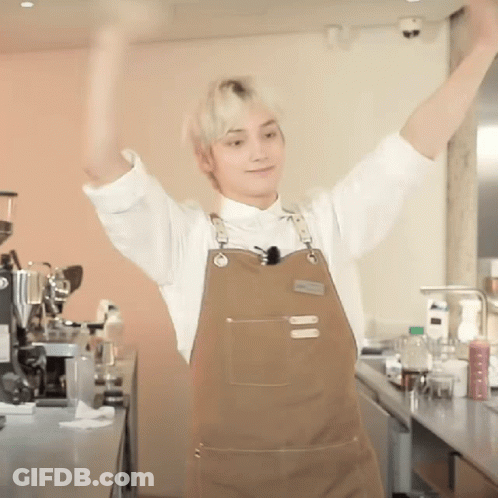 Man In Apron With Arms Up In Kitchen GIF