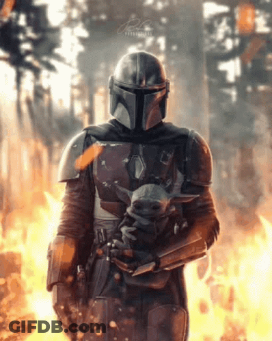 Man In Armor Holding Baby Yoda Before Forest Fire GIF
