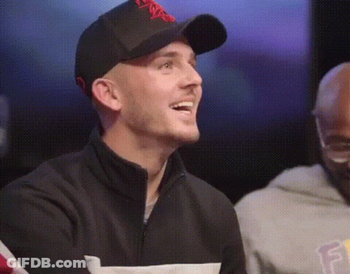 Man In Baseball Cap And Black Jacket Smiling Beside Another Man GIF