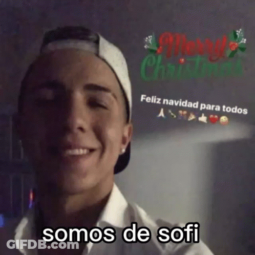 Man In Baseball Cap And White Shirt Smiling At Merry Christmas Sign GIF