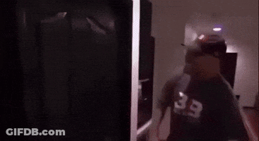 Man In Baseball Cap Standing In Front Of Door GIF
