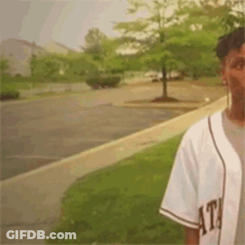 Man In Baseball Jersey On Parking Lot Sidewalk GIF