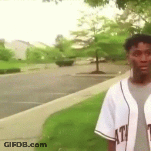Man In Baseball Uniform On Sidewalk In Park GIF