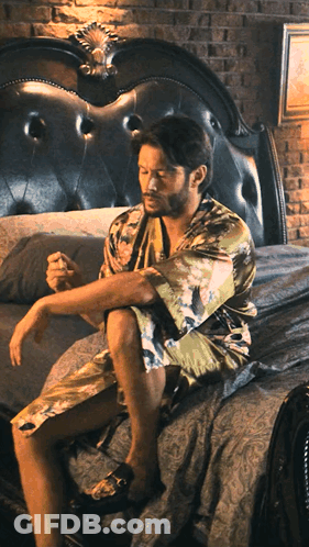 Man In Bathrobe Sitting On Bed GIF