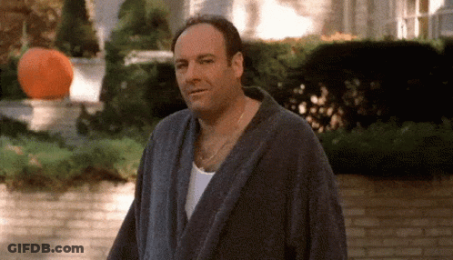 Man In Bathrobe Standing By Brick Wall GIF