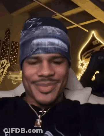 Man In Beanie And Necklace Sitting On Bed GIF