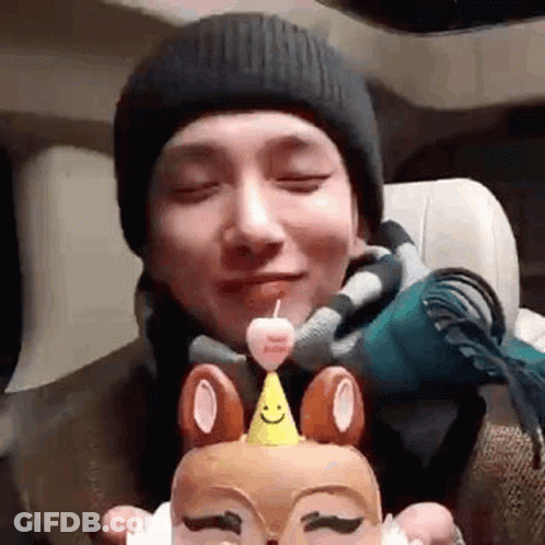 Man In Beanie Holding Birthday Cake With Candle GIF