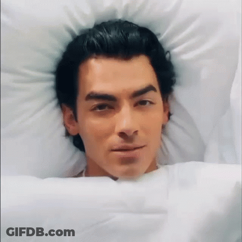 Man In Bed Head On Pillow Looking At Camera GIF