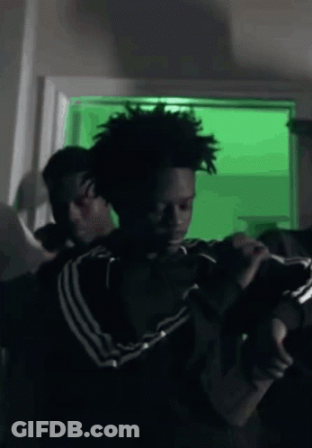 Man In Black Adidas Jacket Holding Gun On Green GIF