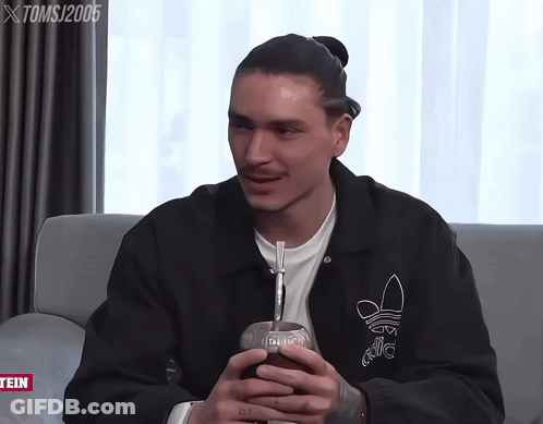 Man In Black Adidas Jacket On Grey Couch GIF
