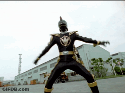 Man In Black And Gold Costume In Front Of White Building GIF