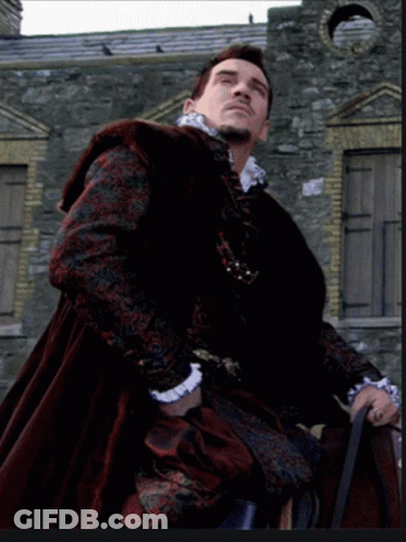 Man In Black And Red Coat In Front Of Stone Wall GIF