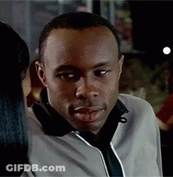 Man In Black And White Jacket In Front Of Mr Roco Sign GIF
