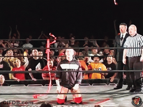 Man In Black And White Jacket In Wrestling Ring With Referees GIF