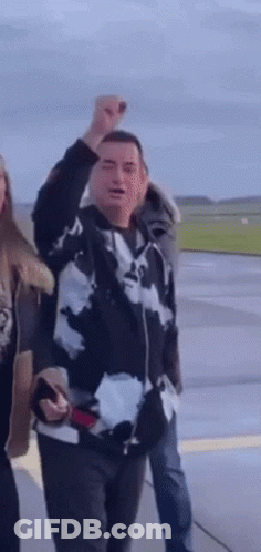 Man In Black And White Jacket Raises Fist GIF