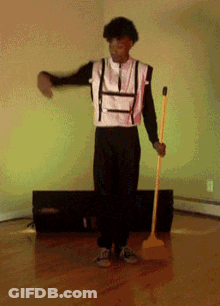 Man In Black And White Outfit Holding Yellow Mop GIF