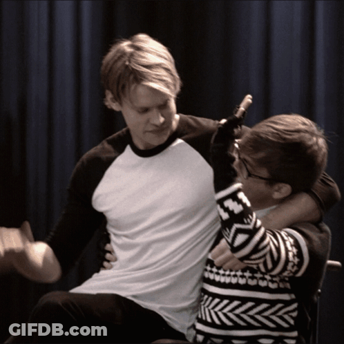 Man In Black And White Sweater Holding Another Man GIF