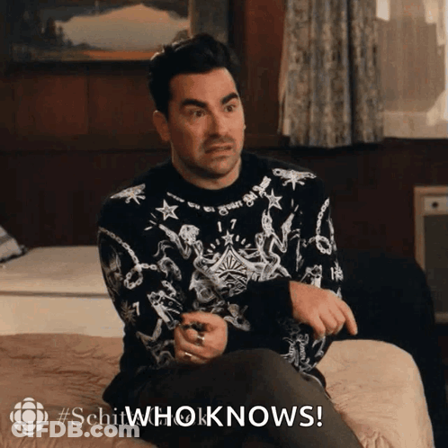 Man In Black And White Sweater Sitting On Bed Saying Schitwhoknows GIF